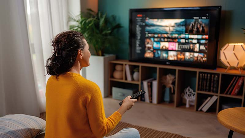 Mulher na sua sala a ver televisão